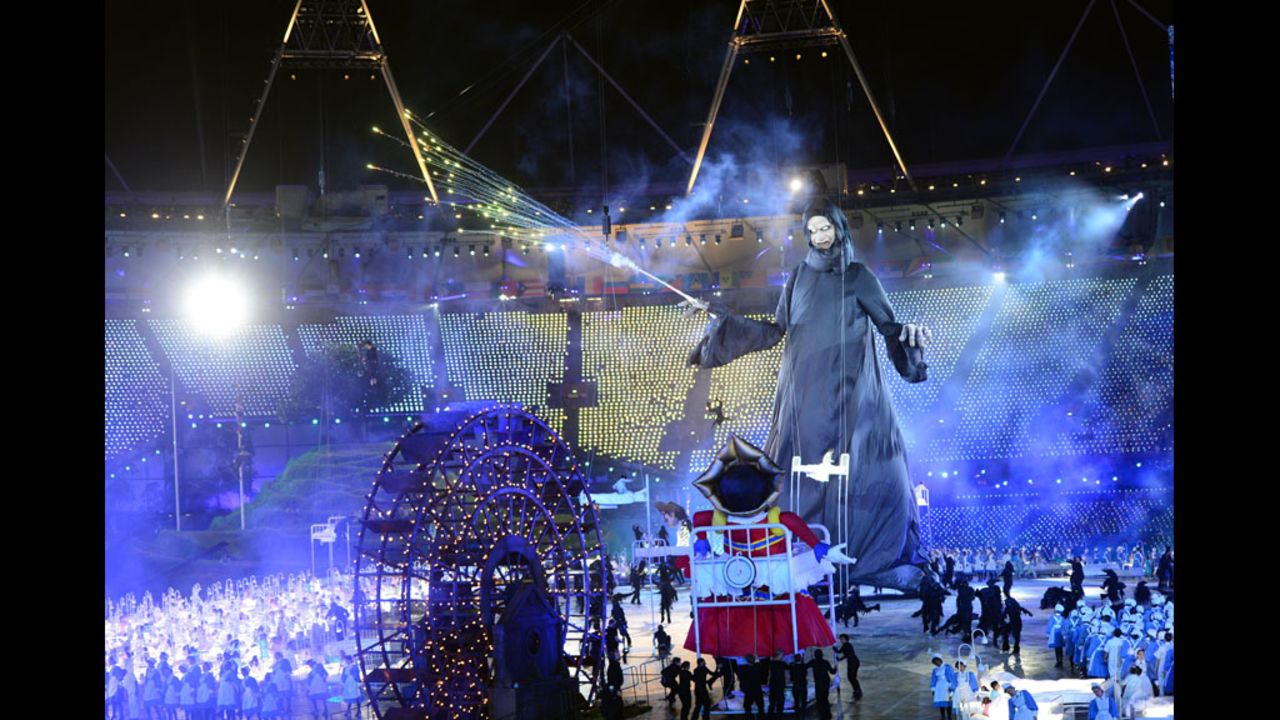 Giant puppets depicting Lord Voldemort, center, from the Harry Potter books and the Child Catcher from "Chitty Chitty Bang Bang" swirl around the stage in the opening ceremony.