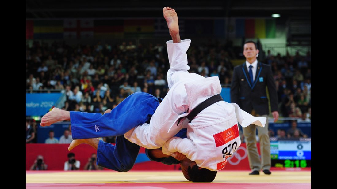 Felipe Kitadai of Brazil, in blue, competes with Rishod Sobirov of Uzbekistan in a judo match.