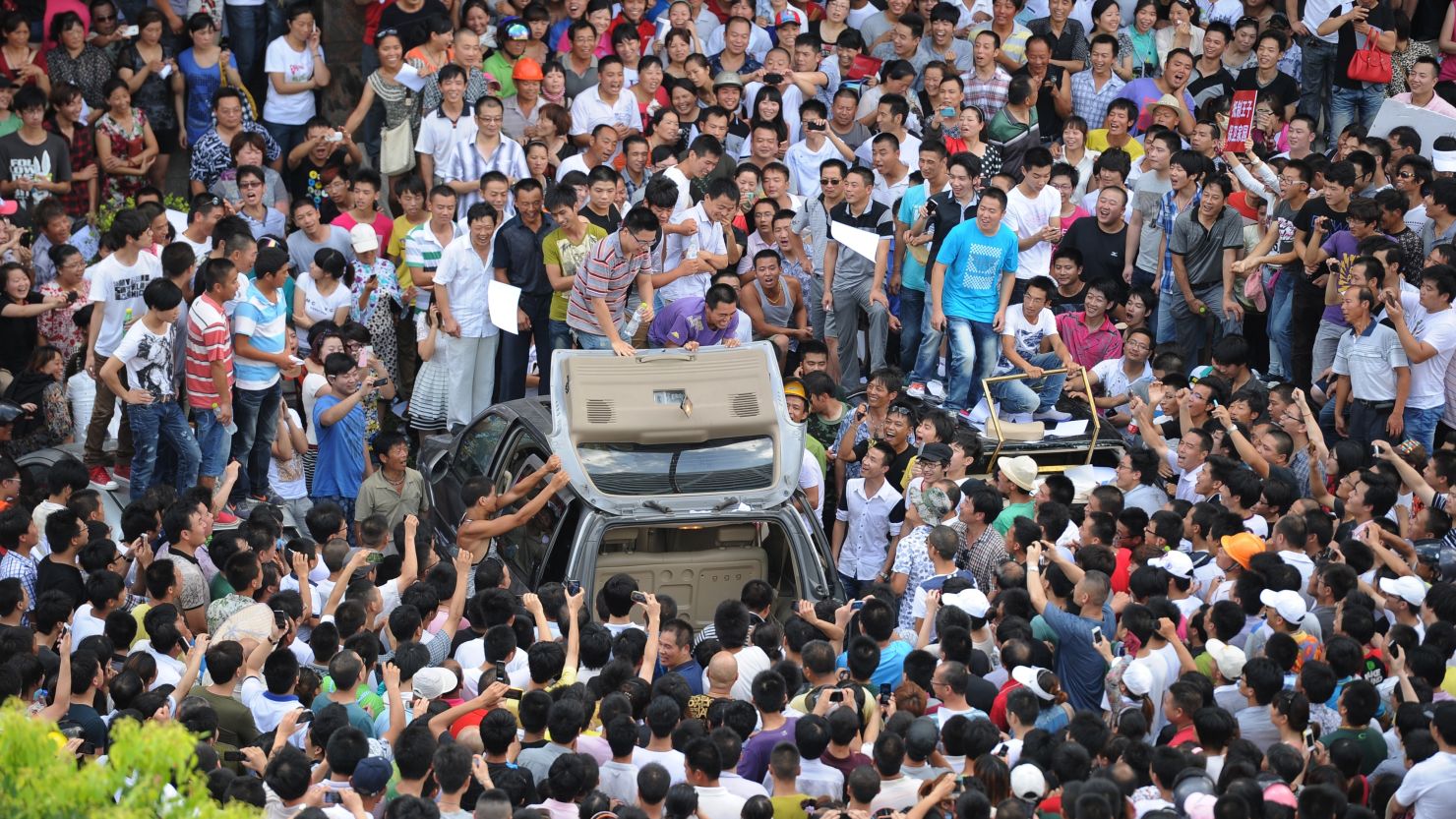 Demonstrators protesting industrial pollution destroy a car in the compound of local government offices in Qidong, China.
