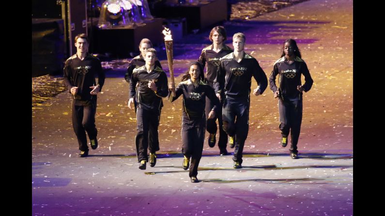 Young athletes carry the Olympic torch toward the cauldron during the opening ceremony.