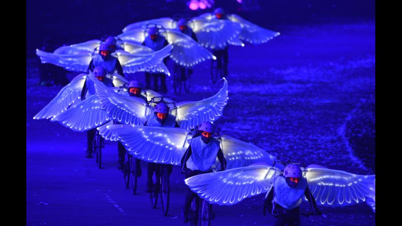 Artists wearing wings and riding bicylces perform during the ceremony.