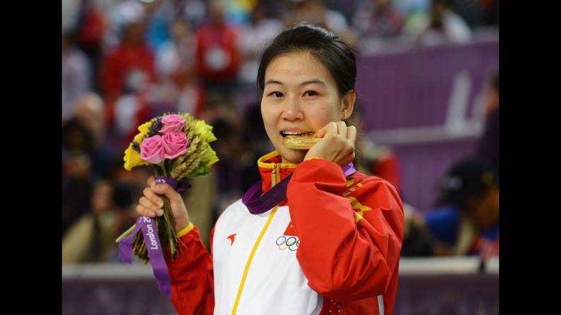 Having won the first gold medal of the Games, Siling Yi of China celebrates her victory during the ceremony for the women's 10-meter air rifle shooting.