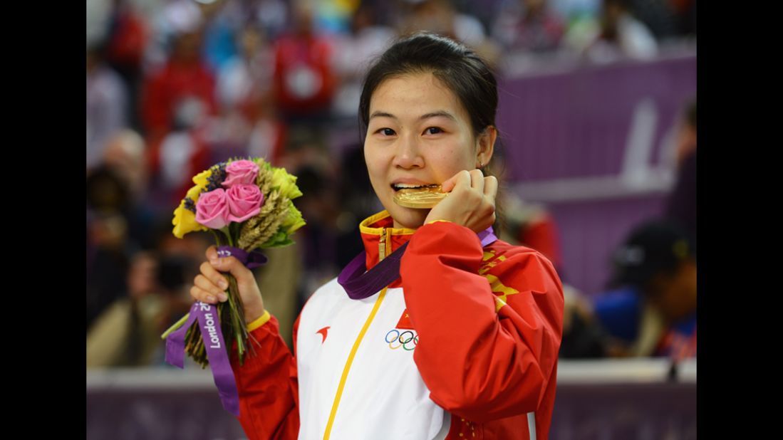 Having won the first gold medal of the Games, Siling Yi of China celebrates her victory during the ceremony for the women's 10-meter air rifle shooting.
