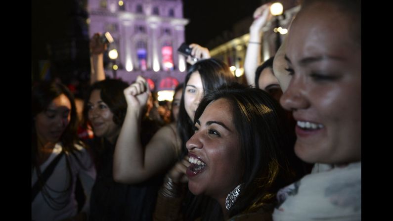 People cheer as they watch the opening ceremony on an outdoor screen at Piccadilly Circus.