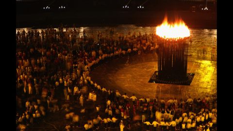 Participants look on as the Olympic flame burns in the cauldron.