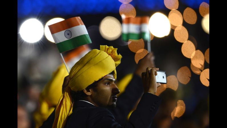 A member of India's delegation takes a picture as he parades during the opening ceremony.