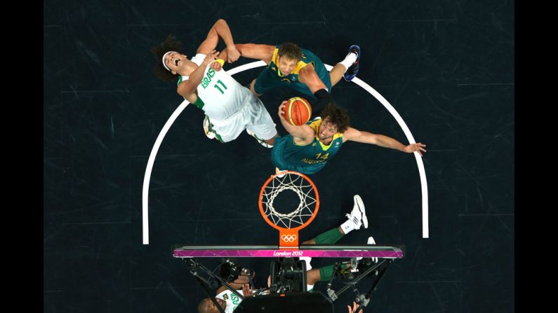 Brazil's Anderson Varejao, No. 11 in white, gets fouled by Australia's David Andersen, No. 13, as Anderson teammate Matt Nielsen goes for the rebound during the Brazil-Australia men's basketball game.