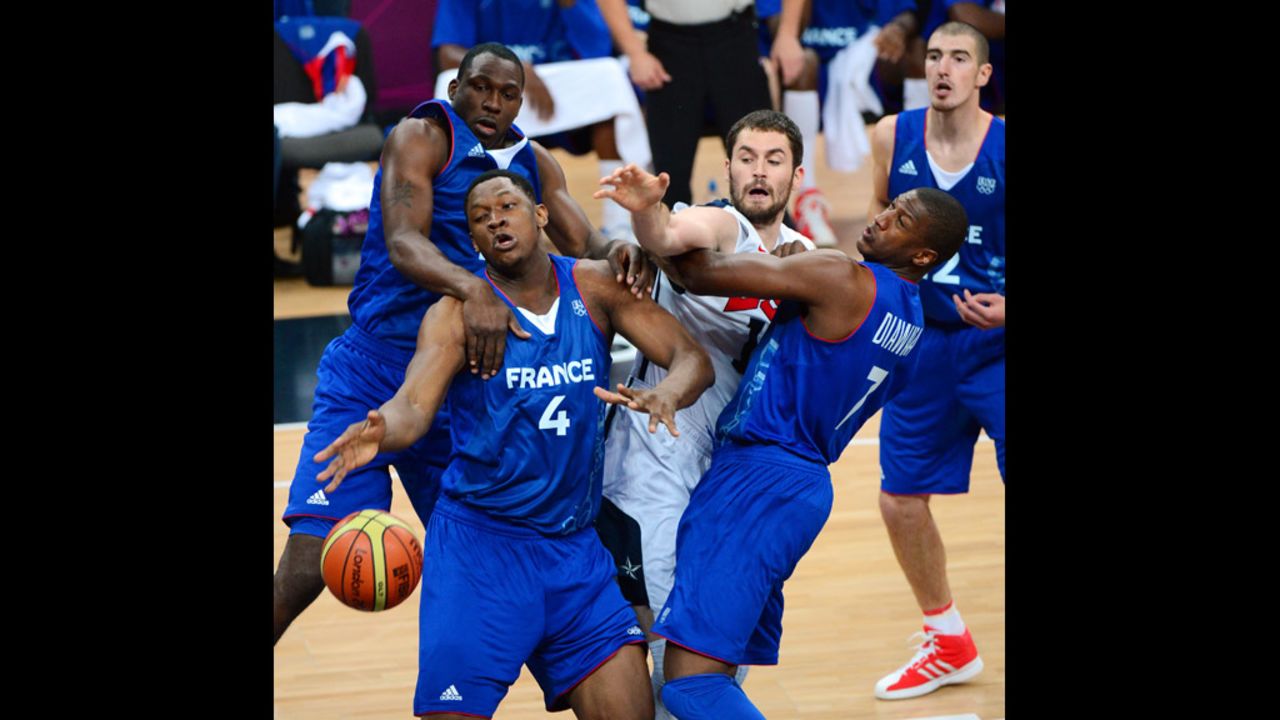 French center Kevin Seraphin, No. 4 in blue, fends off a challenger during the U.S.-France preliminary round match.