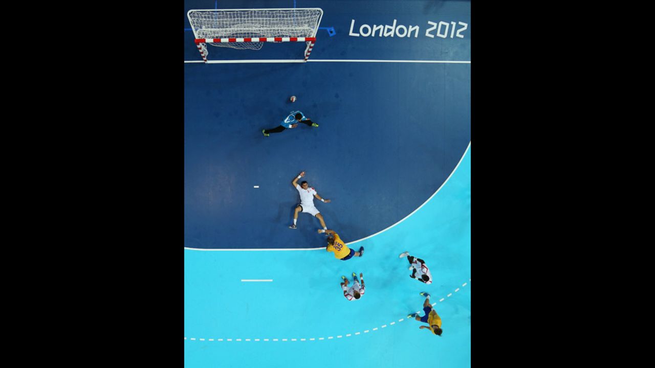 Sweden's Andreas Nilsson, No. 35 in yellow, scores past Issam Tej and goalkeeper Marouen Maggaiz of Tunisia during a men's handball preliminary match.