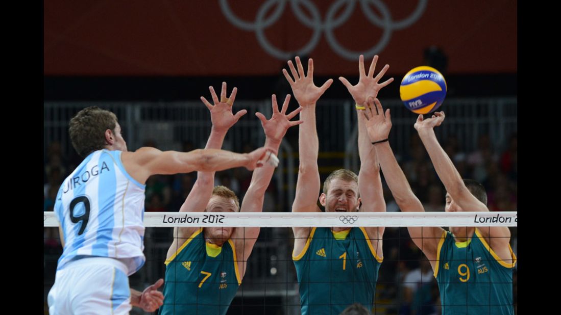 Argentina's Rodrigo Quiroga, left, spikes as Australia's team attempts to block during men's volleyball action between Australia and Argentina.