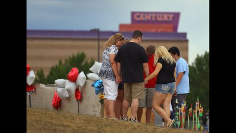 Visitors pray together around a cross erected at a memorial setup across the street from the Century 16 movie theatre on July 28, 2012 in Aurora, Colorado where a gunman opened fire during a screening.