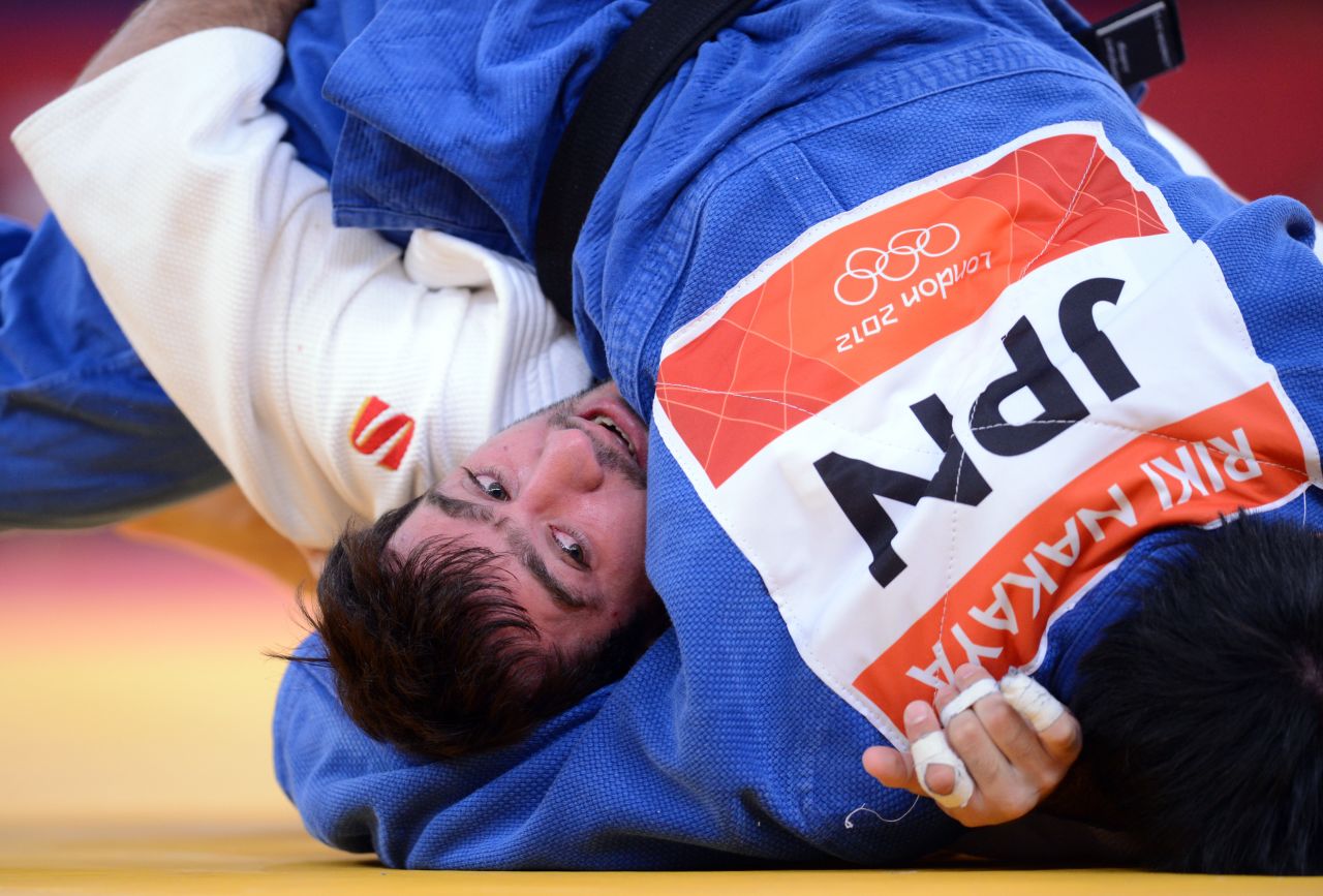 Russia's Mansur Isaev, in white, peers out from under Japan's Riki Nakaya during the men's 73-kilogram judo contest Monday.
