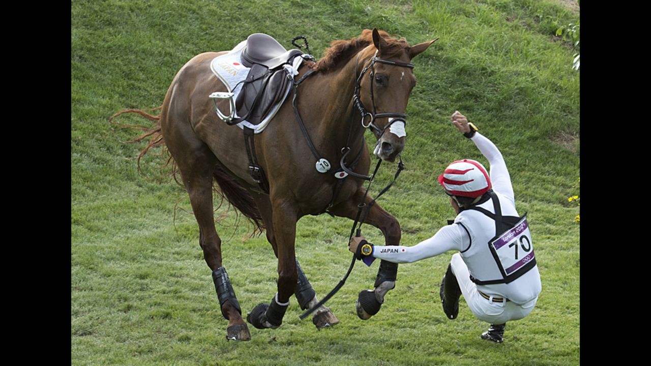 Japan's Yoshiaki Oiwa falls off his horse as he competes in the cross country competition on Monday.