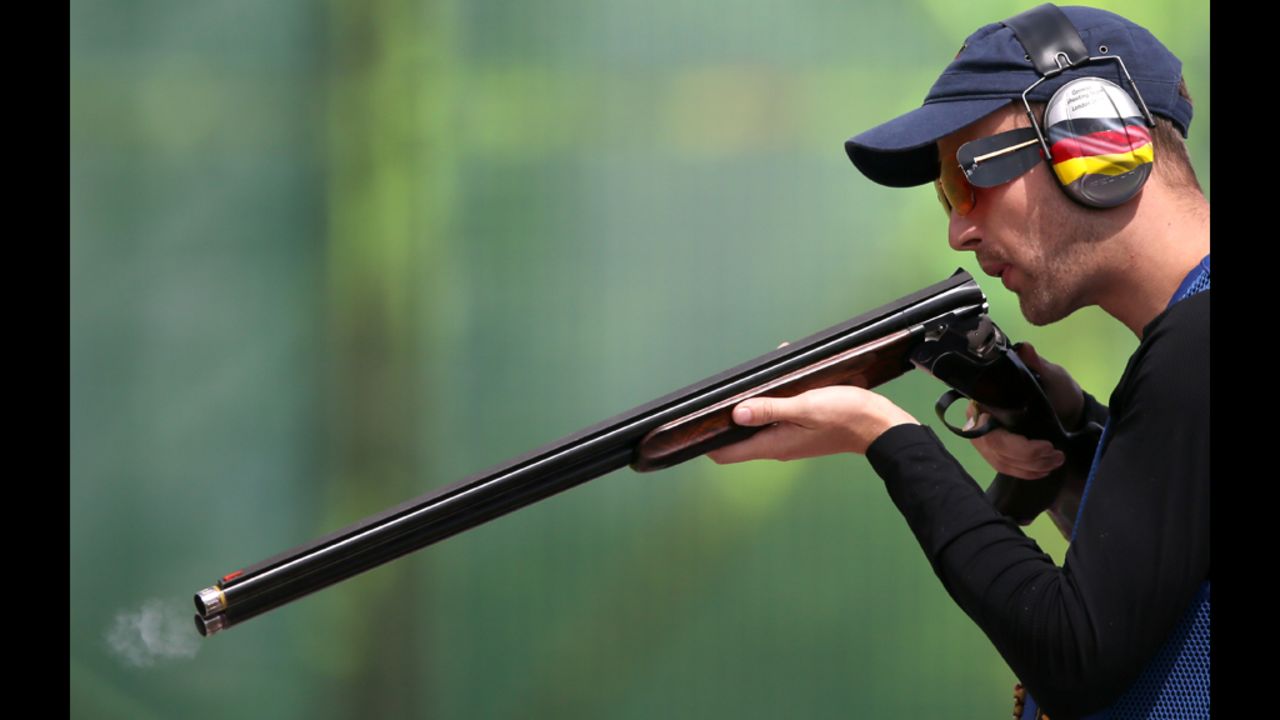 Germany's Ralf Buchheim blows in the barrel of his rifle as he competes in the men's skeet qualification on Monday.