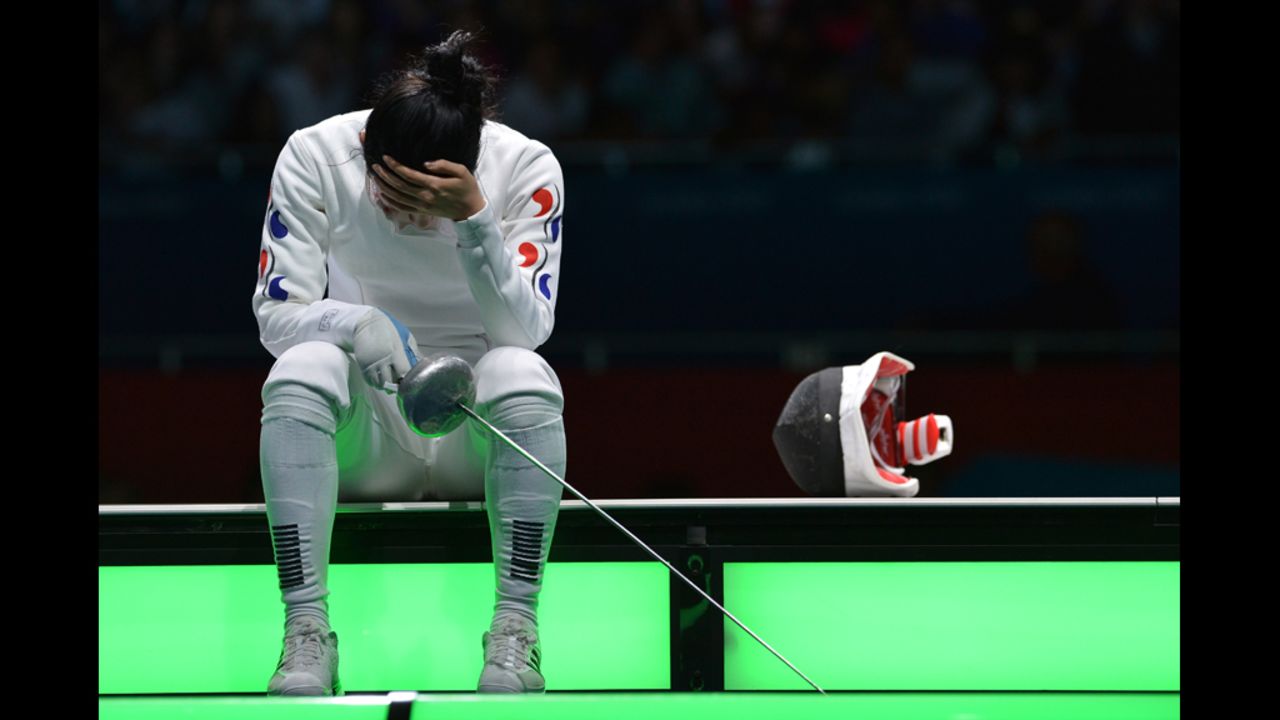 South Korea's  A Lam Shin sits on the fencing field at the end of her women's epee semifinal bout against Germany's Britta Heidemann. The distraught South Korean eventually had to be escorted away.