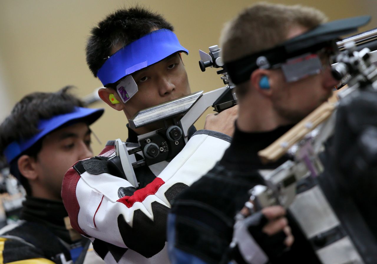 China's Zhu Qinan, center, competes in the men's 10-meter air rifle qualifying round at the Royal Artillery Barracks in London on Monday.