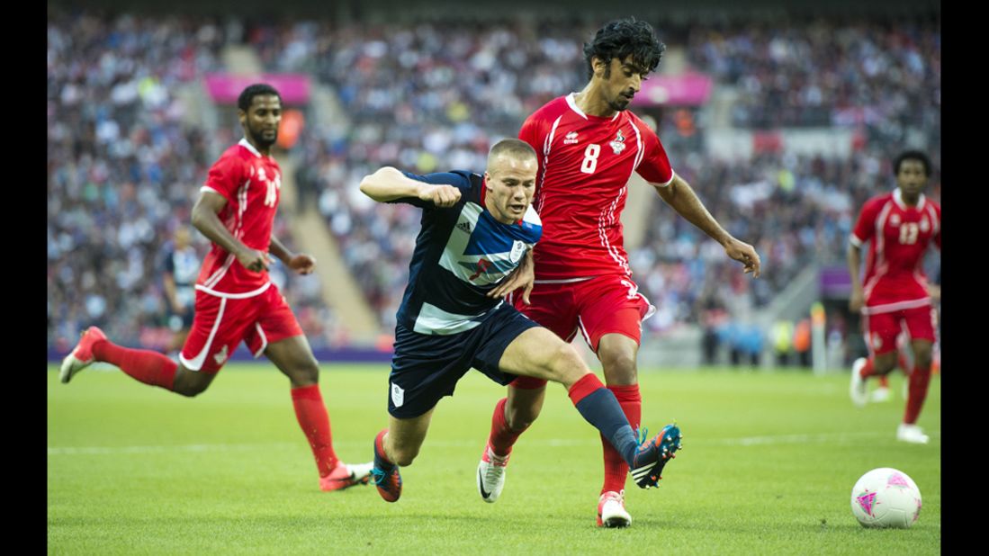 Britain's Tom Cleverley, center, vies for the ball with United Arab Emirate's Hamdan Al-Kamali, right.