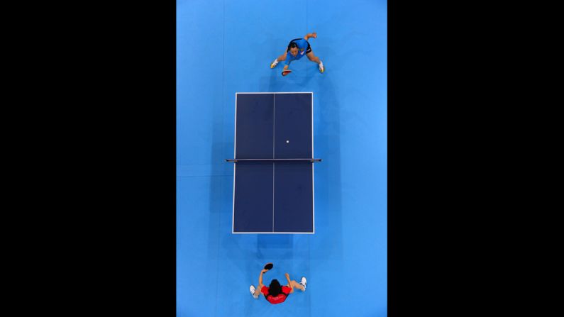 Japan's Kasumi Ishikawa, in red, faces off against Wang Yuegu of Singapore during a women's singles table-tennis match Tuesday.