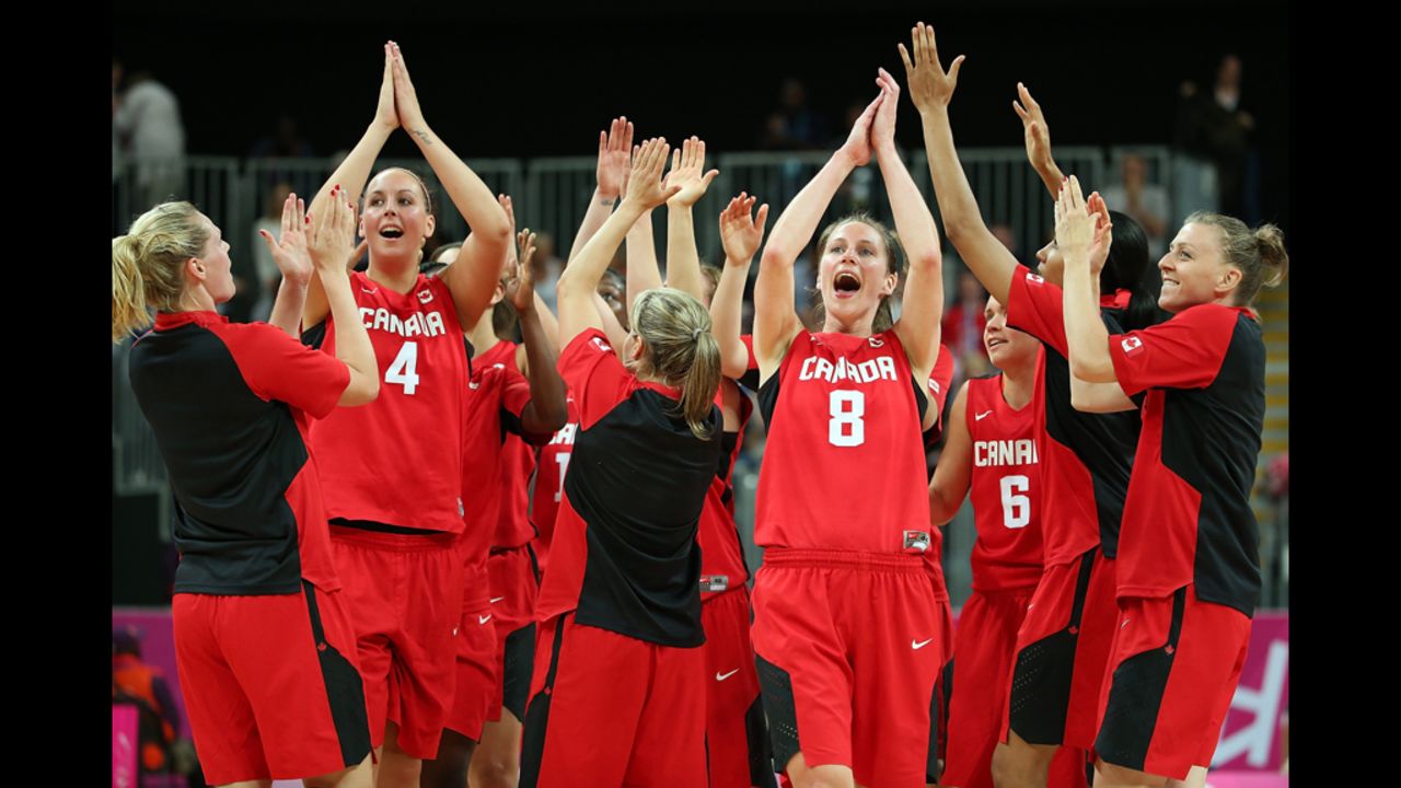 No. 4 Krista Phillips and No. 8 Kim Smith of Canada celebrate with teammates after defeating Great Britain in the women's basketball preliminary round match.