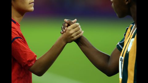 Japan and South African players shake hands before their women's football first-round match Tuesday.