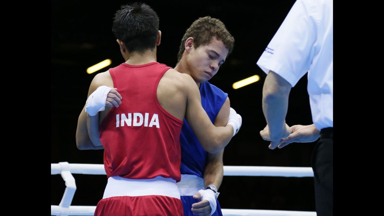 India's Devendro Singh Laishram, left, embraces Bayron Molina Figueroa of Honduras after stopping the Honduran in the first round of their light flyweight boxing match.
