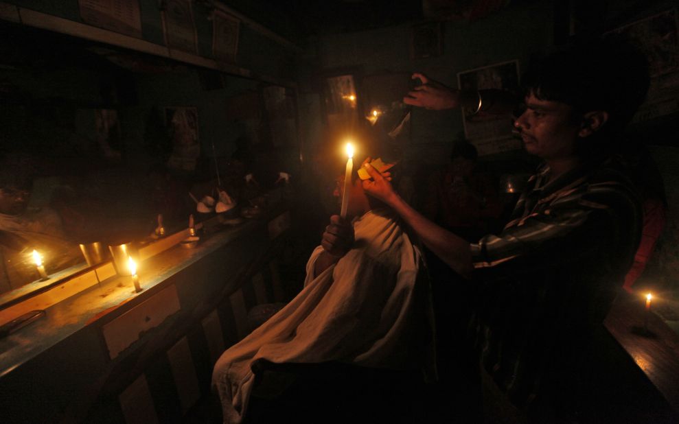 A customer holds a candle as he gets his hair cut at a barber shop in Kolkata on Tuesday.