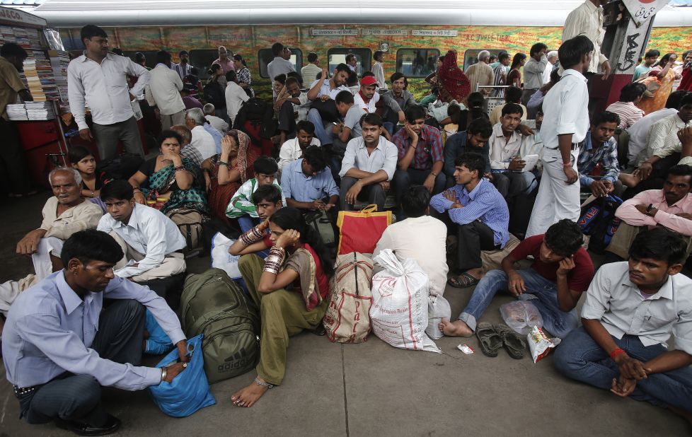 Passengers sit on the platform at train station in New Delhi on Tuesday.