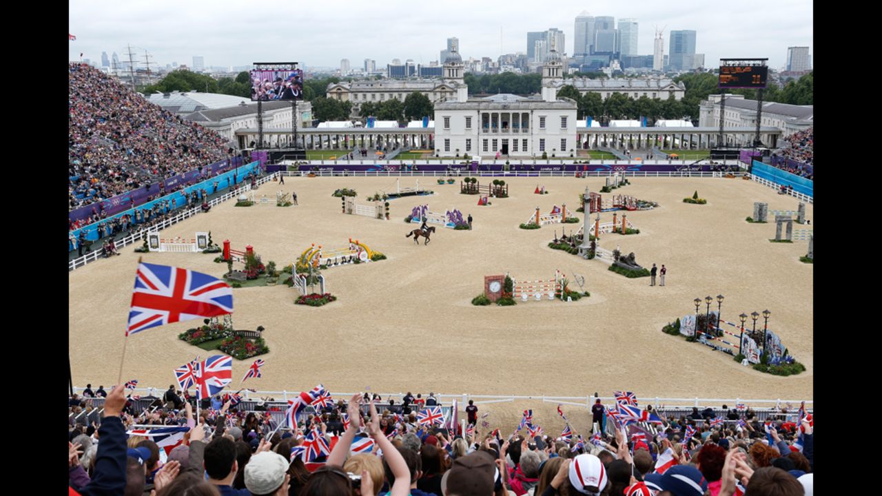 Fans wave Union Jack flags as Britain's William Fox-Pitt, riding Lionheart, performs Tuesday in the show-jumping qualifying equestrian event at Greenwich Park.