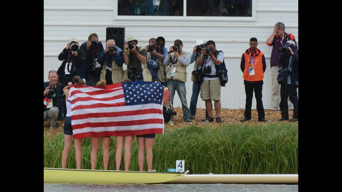 The U.S. team stands wrapped in the American flag on the podium after winning the bronze medal in the women's quadruple sculls final of the rowing event.
