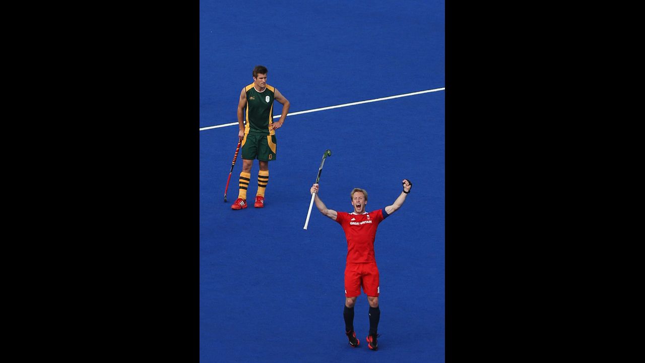 Captain Barry Middleton, in red, celebrates an equalizing goal in front of Lloyd Norris Jones of South Africa during their men's preliminary hockey match.