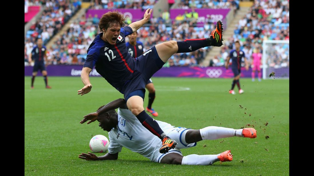 Gotoku Sakai of Japan is tackled by Wilmer Crisanto of Honduras during their first-round soccer match.