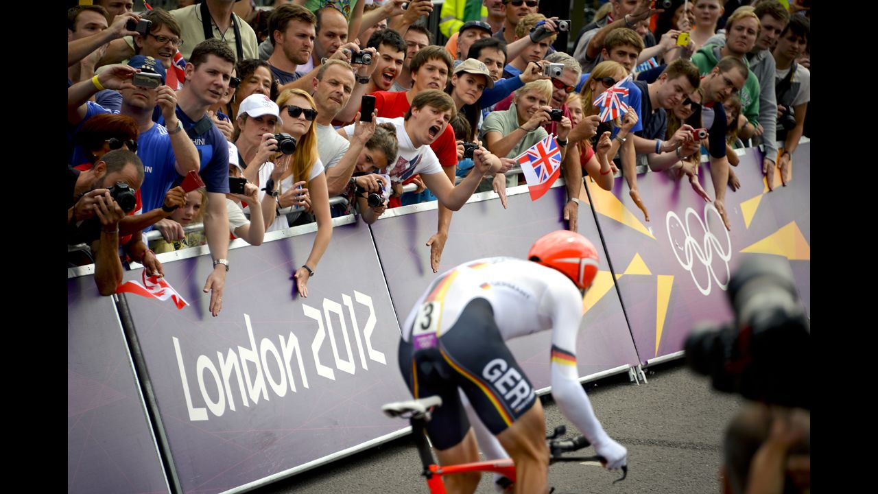 The crowds cheer for German silver medalist Tony Martin as he exits the gate of Hampton Palace to start the men's individual time trial road cycling event.