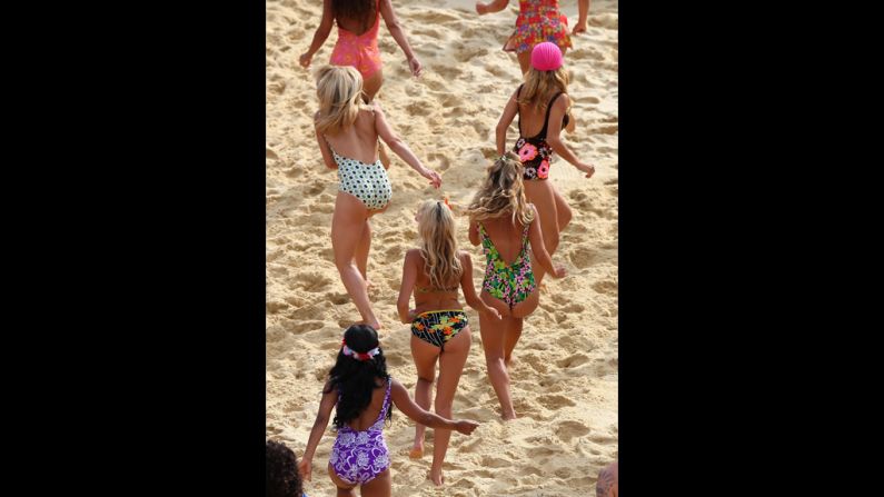 Dancers run from the court Wednesday during the women's beach volleyball preliminary match between China and Greece.