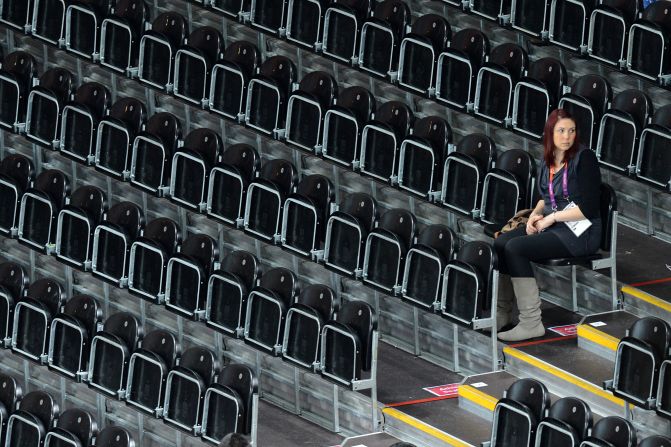 A woman sits in empty stands Wednesday during a women's preliminary volleyball match between the Dominican Republic and Japan.
