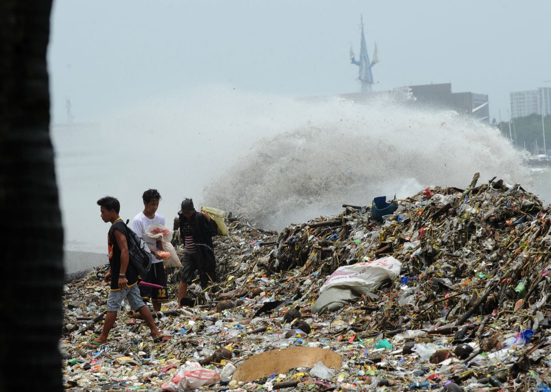 People collect recyclable material from debris washed ashore in Manila on Wednesday, August 1, after heavy rain from Typhoon Saola.