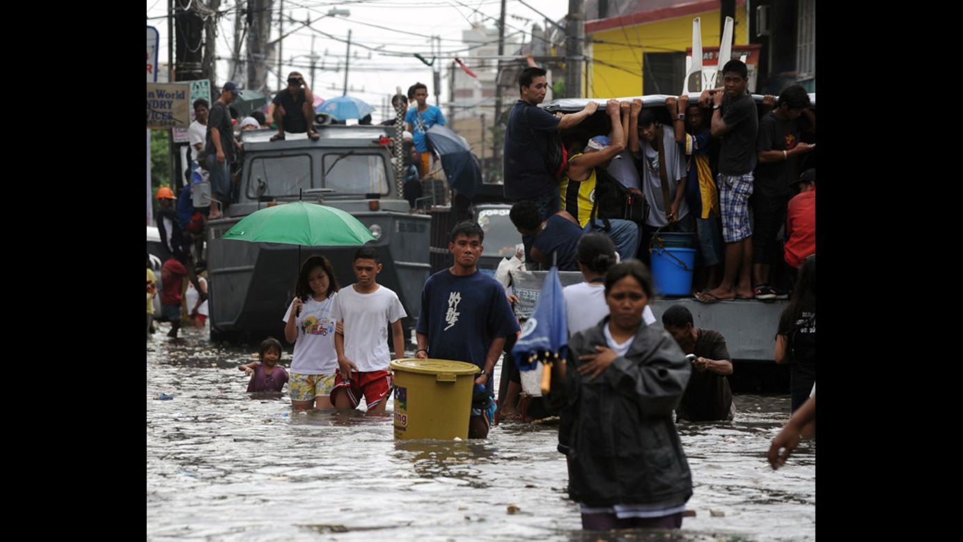 Residents maneuver through a flooded street Wednesday in Navotas. 