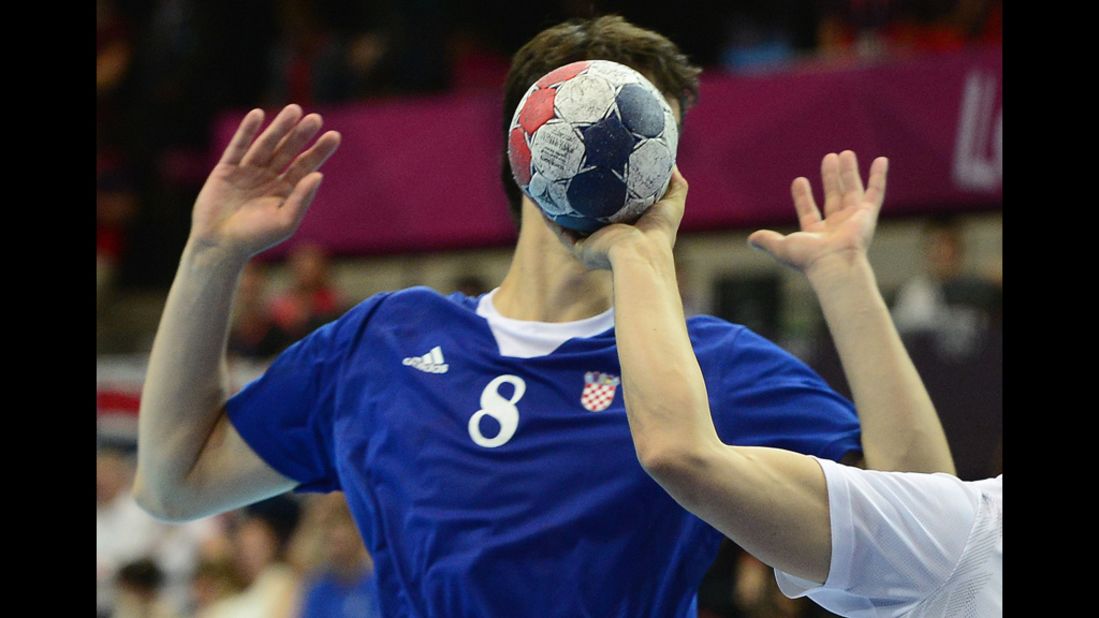 Croatia's Marko Kopljar disappears behind the ball during a men's preliminary handball match between Croatia and Hungary.