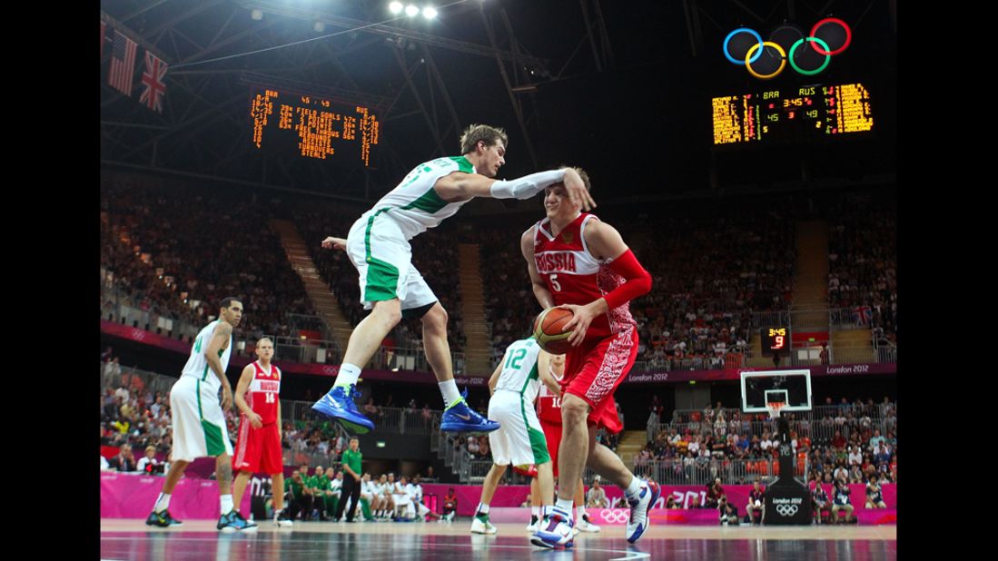 Russia's Timofey Mozgov receives an arm to the head as he looks to shoot against Brazil's Tiago Splitter in the second half of the men's basketball preliminary round match.