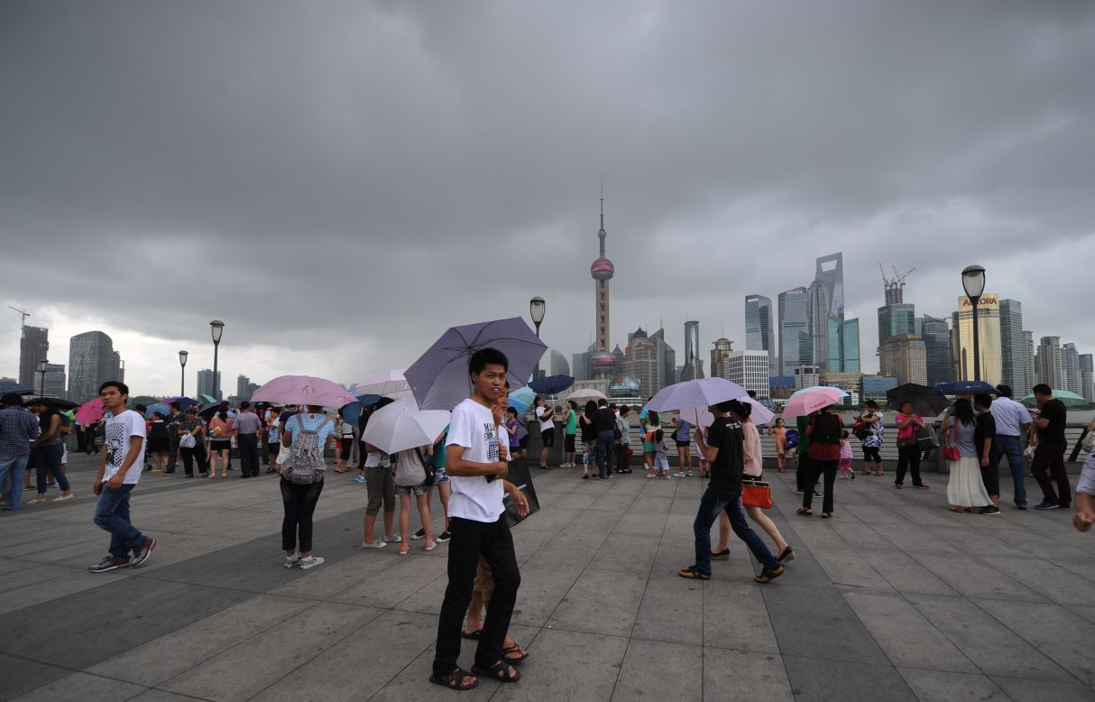 People walk along the Shanghai Bund on Thursday as storm clouds gather over the Huangpu River.  The typhoon was expected to strike south of Shanghai later Thursday.
