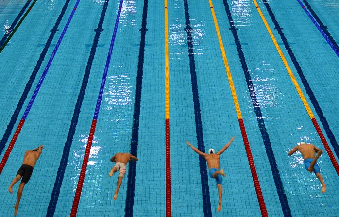 Competitors dive into the pool at the start of the men's 50-meter freestyle heat.