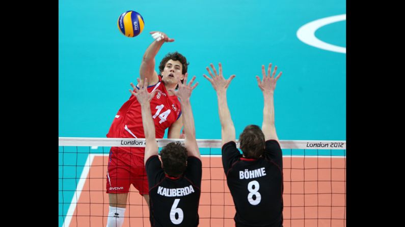 Aleksandar Atanasijevic of Serbia spikes the ball against Denys Kaliberda and Marcus Bohme of Germany.