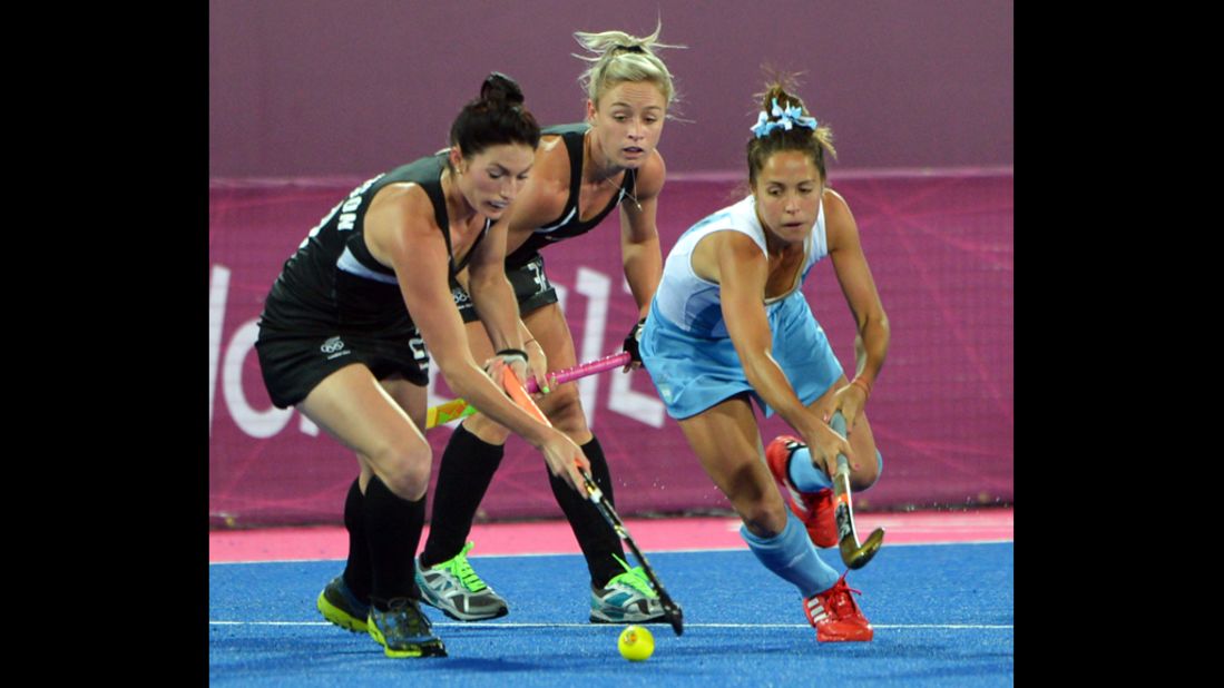 Ella Gunson, left, and Anita Punt, center, of New Zealand challenge Rocio Sanchez Moccia, right, of Argentina during the women's hockey preliminary round match.