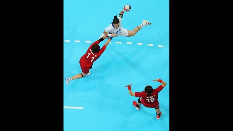 France' s Alexandra Lacrabere, in white, shoots over South Koreans Eun Hee Ryu, left, and Im Jeong Choi during a women's handball preliminaries match.