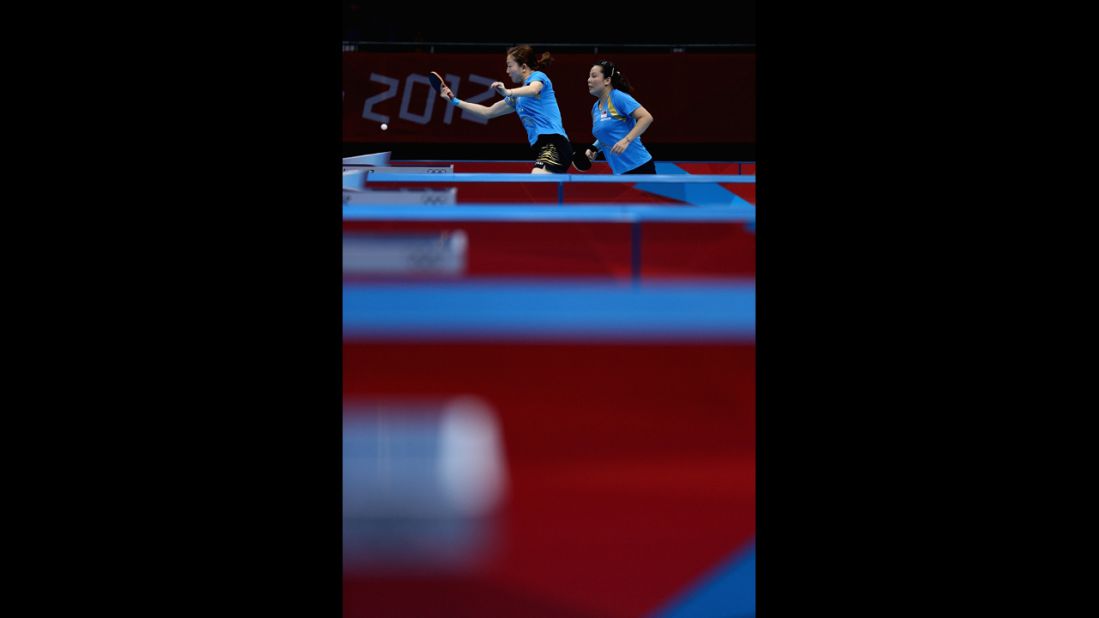 Yuegu Wang, left, and Jiawei Li of Singapore face off against Polish competitors during a first-round match in women's team table tennis.