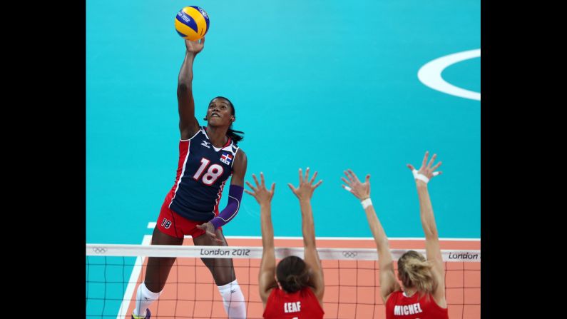 Bethania de la Cruz de Pena, left, of  the Dominican Republic spikes the ball as Britain's Savanah Leaf, center, and Ciara Michel defend during women's volleyball action.