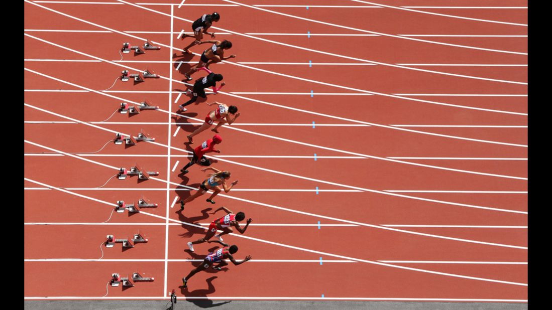 Athletes leave the blocks at the start of the women's 100-meter heat.