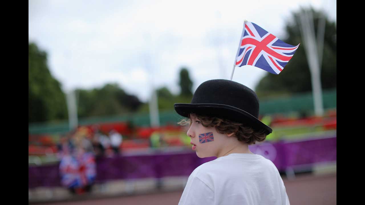 A boy watches as athletes make their way past Buckingham Palace while competing in the cycling leg of the women's triathlon at Hyde Park.