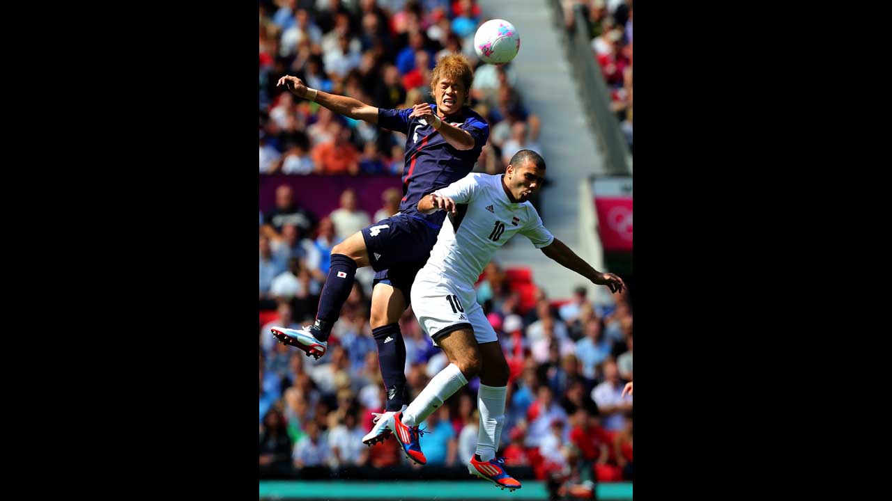Hiroki Sakai of Japan clashes with Emad Moteab of Egypt to score during the men's football quarterfinal match at Old Trafford in Manchester, England.