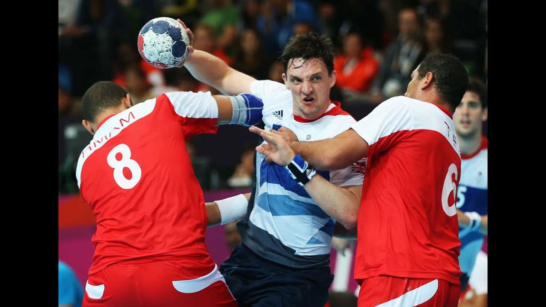 Wissem Hmam, left, and Issam Tej, right, of Tunisia defend against Christopher McDermott of Great Britain during a men's handball preliminaries match in group A.
