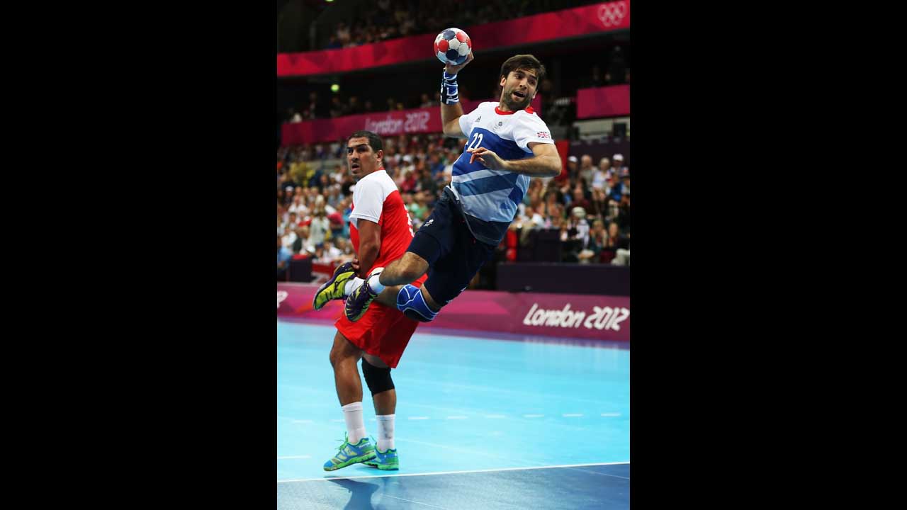 Robin Garnham of Great Britain shoots past Issam Tej of Tunisia during a men's handball preliminaries match in group A.